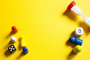 Layout of board games on a yellow background dice, chips, hourglass timer. Entertainment at home for children and adults. Copy space photo