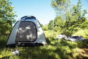Installed tourist tent in a camping in nature in the forest. Domestic tourism, active summer holidays, family adventures. Ecotourism, sport, hike. Copy space, mock up photo