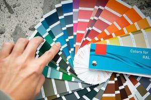 Selection of the paint color for decorative home repairs to the palette with layouts. A fan of shades in your hand inside the home. Repair and construction, paint and varnish coating photo