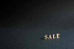 inscription Sale of wooden letters on a black background. Black Friday, discounts, sale, shopping, interest sign. Space for text photo