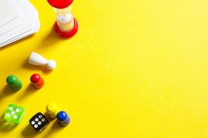 Layout of board games on a yellow background dice, chips, hourglass timer. Entertainment at home for children and adults. Copy space photo