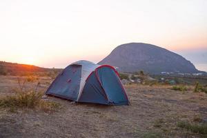 Installed tourist tent in the mountains with a view of the sea and sunrise. Domestic tourism, active summer trip, family adventures. Ecotourism, camping, sports mountain hiking. Ayu-Dag, Crimea. photo