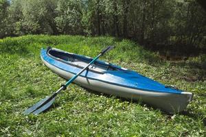 Tourist canoes with paddles stand on the river coast in summer on a water hike. Rafting on inflatable and frame double and triple kayak boats, family trip, extreme adventure in summer photo