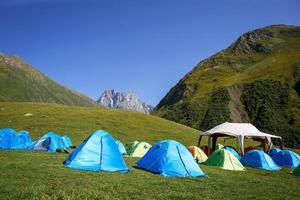 camping turístico en las montañas de muchas tiendas y refugios para subir a la cima de la montaña - un campamento alpino. noche en la naturaleza. georgia, montaña chaukhi, pueblo de yute foto