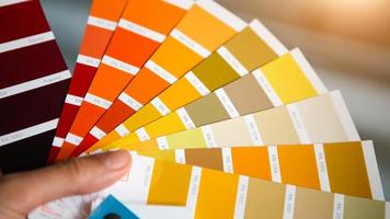 Selection of the paint color for decorative home repairs to the palette with layouts. A fan of shades in your hand inside the home. Repair and construction, paint and varnish coating photo