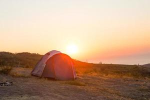 Installed tourist tent in the mountains with a view of the sea and sunrise. Domestic tourism, active summer trip, family adventures. Ecotourism, camping, sports mountain hiking. Ayu-Dag, Crimea. photo