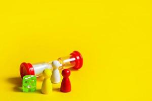 Layout of board games on a yellow background dice, chips, hourglass timer. Entertainment at home for children and adults. Copy space photo