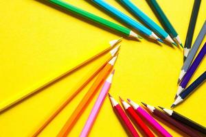 Set of colorful pencils on a yellow background is laid out in a circle in the shape of the square. Copyspace, frame. Back to school, artist, drawing lessons. Stationery for creativity, draw