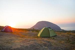 Installed tourist tent in the mountains with a view of the sea and sunrise. Domestic tourism, active summer trip, family adventures. Ecotourism, camping, sports mountain hiking. Ayu-Dag, Crimea. photo