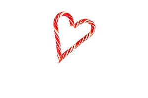 Two red striped candy canes of Santa are stacked in the shape of a heart on white background. Isolate, frame. Christmas, new year, Valentine's day, winter holiday atmosphere for lovers and loved ones photo