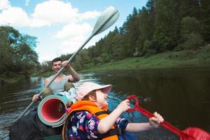 Family kayak trip. Father and daughter rowing boat on the river, a water hike, a summer adventure. Eco-friendly and extreme tourism, active and healthy lifestyle photo