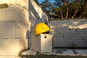 Construction yellow hardhat and key to house on window of housing made of blocks of porous concrete. Turnkey construction, future home, engineering, building. Work safety. Copy space photo