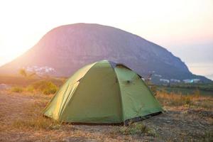 Installed tourist tent in the mountains with a view of the sea and sunrise. Domestic tourism, active summer trip, family adventures. Ecotourism, camping, sports mountain hiking. Ayu-Dag, Crimea. photo