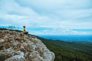 mujer asiática relajarse en las vacaciones. viajar relajarse. jugar si yoga. en el acantilado de roca de montaña. naturaleza de los bosques de montaña en tailandia foto