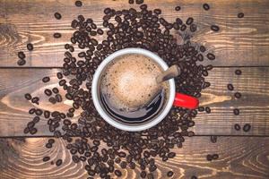 Coffee cup and beans on rustic wooden background. Top view with copyspace for your text. Coffee beans spread on the table. photo