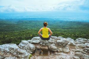 mujer asiática relajarse en las vacaciones. viajar relajarse. jugar si yoga. en el acantilado de roca de montaña. naturaleza de los bosques de montaña en tailandia foto