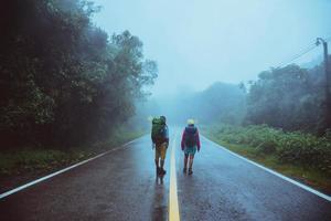 amante del hombre asiático y las mujeres asiáticas viajan por la naturaleza. caminar por la ruta de la carretera. viajando felizmente por la naturaleza. en medio de la neblina lluviosa.