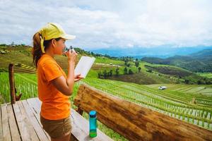 Asian woman travel nature. Travel relax. Standing reading book the balcony of the house. in summer. photo