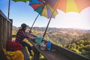 The girl sitting eating noodle in the rural village hanging legs style for viewpoint on the mountain,The local attractions of Mae Hong Son province Thailand. photo