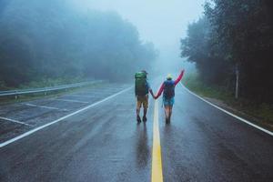 Lover asian man and asian women travel nature. Walk on the road route. traveling nature happily. Amid the mist rainy. photo