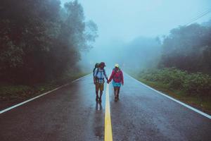 amante del hombre asiático y las mujeres asiáticas viajan por la naturaleza. caminar por la ruta de la carretera. viajando felizmente por la naturaleza. en medio de la neblina lluviosa. foto