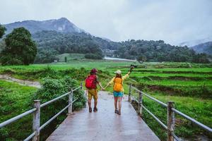 Lover asian man asian women travel nature. Walking a photo the rice field and stop take a break relax on the bridge at  ban mae klang luang in rainy season.