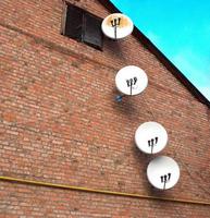 cuatro antenas parabólicas adjuntas en la pared de la casa antigua foto