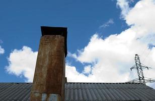 techo de pizarra nubes de tubería oxidada y poste eléctrico foto