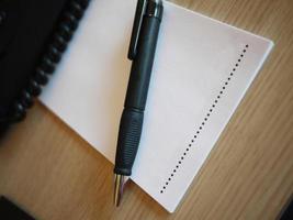 Notepad paper with black pen on the wooden table and telephone cable photo