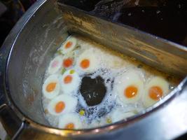 Boiling sweet eggs and Thai Glutinous Rice Balls in large stainless steel pot selling in local night market thailand photo