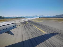 Airplane wing takoff on runway with snow mountain background photo