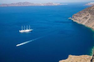 Beautiful bay with sailing boats, Santorini island Greece deep blue sea bay with cliffs and morning haze photo