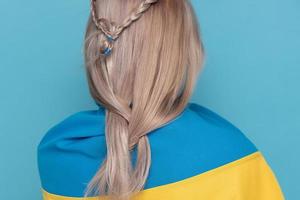 Woman with blue-yellow cloth on her shoulders. Woman back to camera on a blue background. photo