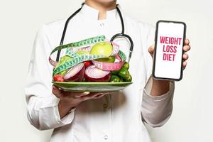 Weight loss diet - Doctor holds fresh fruits and vegetables and smartphone photo