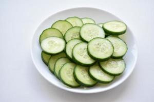 Sliced cucumber slices on a white plate with a fork photo