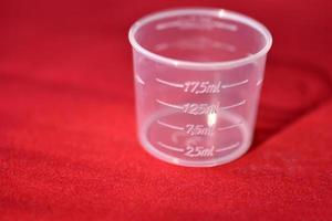 vaso medidor de plástico sobre un fondo rojo foto