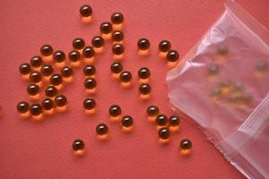 Yellow fish oil balls in a bag on a red background photo