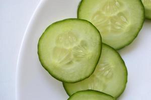Sliced cucumber slices on a white plate with a fork photo