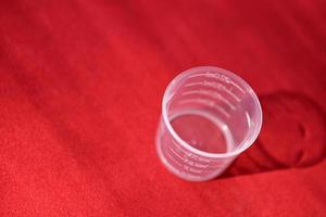 Plastic measuring beaker on a red background photo