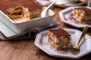 Traditional Italian Tiramisu dessert in baking dish on wooden background or table