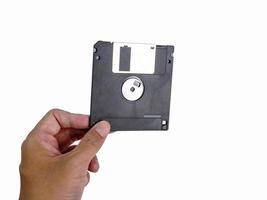 mano sosteniendo un disquete un disco, inserte el lector. para leer y escribir datos es tecnología antigua que se ha utilizado durante mucho tiempo tiene forma rectangular, fondo blanco, tiene un camino de recorte foto