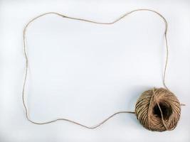 coiled raw rope Made of various fibers into a long rope. is stretched into a frame with a space to insert text in the middle For brown crafts, white background isolated, studio shot. photo