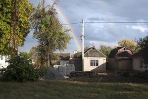 autumn rainbow behind the house and trees photo