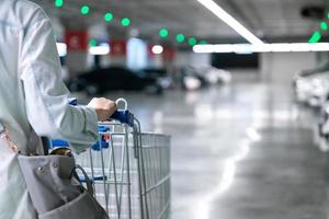 mujer feliz con carrito de compras cerrado o carrito en el estacionamiento de un mercado fresco para ama de casa saludable en una tienda de supermercado