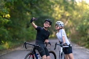 happy couple cycle selfie with smart phone during ride on rode in countryside for health life style photo