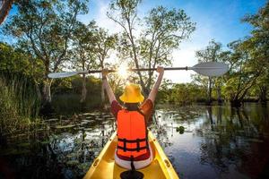 happy woman kayaking with kayak boat in nuture lake behind sea and beach before sunset time for relax and extreme water sport photo