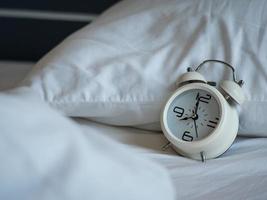 Retro white alarm clock On the white mattress in the bedroom photo