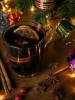 Hot drink alcohol,Mulled red wine in a cup of glass spices cinnamon stick and citrus fruit.decoratied fir festive on wood table.Celebration christmas and Happy New Year Concept. photo