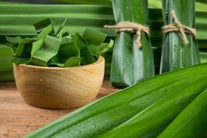 hojas de pandan y pandan en una taza de madera preparada para hervir o secar jugo de pandan o pastel de pandan antes de ir a cocinar. filmado en el estudio foto