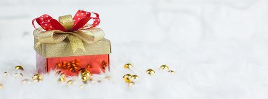 feliz navidad caja de regalo de oro con cintas rojas sobre fondo de algodón de visón blanco.seleccione el enfoque y copie el espacio para su texto.banner concepto de navidad y san valentín foto